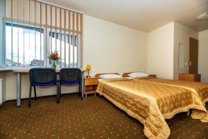a bedroom with a bed and a desk and two chairs at Apartamentai "Tenisas" in Palanga
