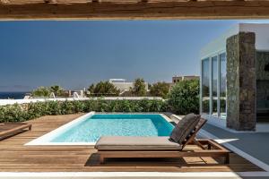 a swimming pool with a chaise lounge and a villa at Villa Ananta Mykonos in Mikonos