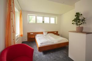 una camera da letto con un letto e una sedia rossa di Hotel Garni Brigitte a Bürserberg