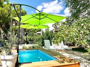 a green umbrella sitting next to a swimming pool at Summer Apartment in Makarska