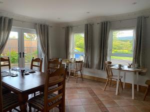 una sala da pranzo con tavoli, sedie e finestre di Muff Village Bed & Breakfast a Muff