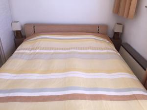 uma cama com um cobertor listrado em cima em Gezellig appartement voor het gezin em Middelkerke