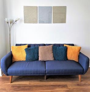 a blue couch with colorful pillows in a living room at Beautifully renovated 2 Bed flat - Close to beach in Southend-on-Sea