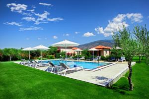 a swimming pool with lounge chairs and umbrellas at Elite Cottages in Káto Lekhónia