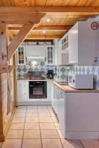 uma cozinha com electrodomésticos brancos e um tecto de madeira em Appartement privatif type chalet cosy et calme em Métabief