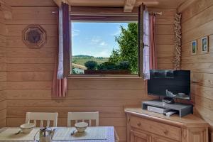 Habitación con mesa, TV y ventana. en Appartement privatif type chalet cosy et calme en Métabief