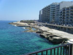 vista su una spiaggia con edifici e sull'oceano di Roma Hotel a Sliema