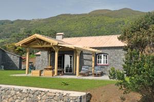 a stone house with a wooden roof and a patio at Azorenhaus am Atlantik - Family House in Urzelina