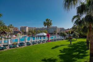 un complexe avec une piscine, des chaises et des palmiers dans l'établissement Arum Barut Collection - Ultra All Inclusive, à Sidé