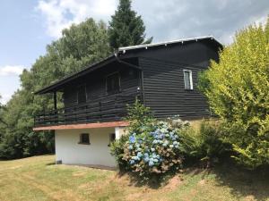 una casa negra con flores delante en Orée du Bois en Abreschviller