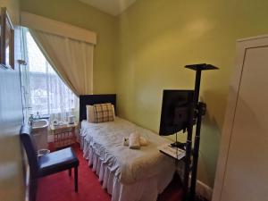 a bedroom with a bed and a tv and a window at Park Guest House in Inverness