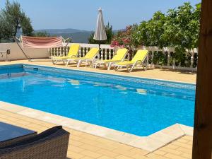 a swimming pool with yellow lounge chairs next to it at casa da ainheira 44 cruz da assumada 8100-296 Loulé in Loulé