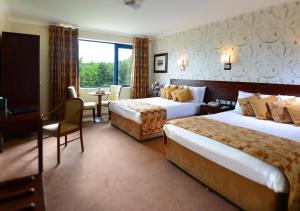 a hotel room with two beds and a desk at Kiltimagh Park Hotel in Kiltimagh