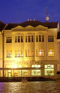 um grande edifício branco à noite com água na frente em Hotel Slávie Pelhřimov em Pelhřimov