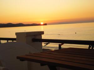 a bench sitting on the beach with the sunset at Abraham Apartments in Acharavi