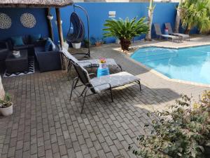 a patio with a chair and a table next to a pool at Palm Beach Guesthouse in Port Elizabeth