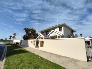 una casa blanca con una valla al lado de una calle en Palm Beach Guesthouse, en Port Elizabeth