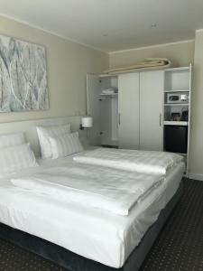 a bedroom with a large white bed with white pillows at Strandhotel Fischland in Dierhagen