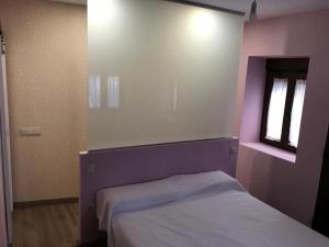 a bedroom with a purple bed and a window at La Plaza Vieja in Cuevas del Valle
