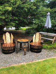 zwei Stühle, einen Tisch, einen Regenschirm und eine Bank in der Unterkunft Kilmore Farmhouse in Drumnadrochit