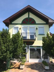 a yellow and green house with a balcony at Kőrös Hotel in Kiskőrös