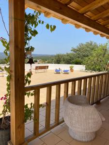 un porche de madera con una silla de mimbre en una terraza en casa da ainheira 44 cruz da assumada 8100-296 Loulé en Loulé