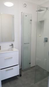 a bathroom with a glass shower and a sink at Morskie Wzgórze Apartamenty in Mechelinki