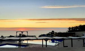 einen Pool mit Wasser und Sonnenuntergang im Hintergrund in der Unterkunft Hotel Miramar Sul in Nazaré