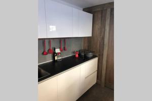 a kitchen with white cabinets and a black counter top at Piccolo paradiso in centro Cervinia in Breuil-Cervinia +16 photos