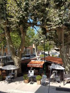 a cafe with tables and umbrellas on a city street at Hôtel Restaurant le Provence in Brignoles