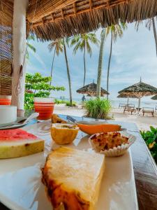 - une table avec de la nourriture sur une plage avec des parasols dans l'établissement Savera Beach Houses, à Jambiani