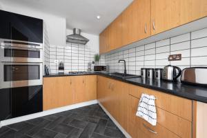 a kitchen with wooden cabinets and black counter tops at The Spinney - Perfect for Contractors, Large Groups & Families in Wolverhampton