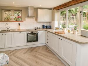 a kitchen with white cabinets and a wooden counter top at Gormire Cottage in Thirsk