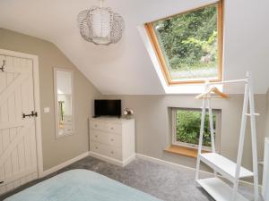 a attic room with a ladder and a window at Gormire Cottage in Thirsk