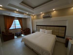 a bedroom with a large white bed and two chairs at Hotel Danat Al Khaleej in Ḩilf +19 photos