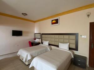 a hotel room with two beds and a tv at Hotel Danat Al Khaleej in Ḩilf