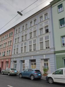 two cars parked in front of a large building at Zentrales & modernes City-Apartment in Graz