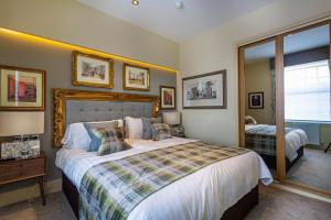 - une chambre avec un grand lit et un miroir dans l'établissement The Rutland Arms Hotel, Bakewell, Derbyshire, à Bakewell