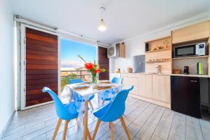 a kitchen and dining room with a table and blue chairs at Studio du Lagon vue mer St Gilles les Bains Centre 500m de la plage in Grand Fond