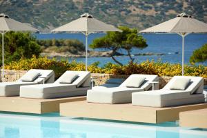 - une rangée de chaises et de parasols blancs à côté de la piscine dans l'établissement Vincci EverEden, à Anavyssos