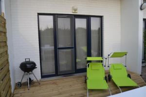 a patio with two green chairs and a grill at Maison à Westende in Middelkerke