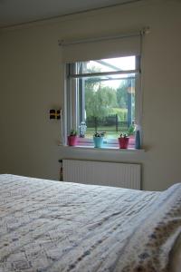 um quarto com uma cama e uma janela com vasos de plantas em Private room for rent in a villa with garden view em Älmhult