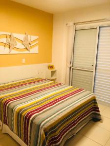 a bedroom with a bed with a colorful striped blanket at Apartamento Alto Padrão - Home Resort Laguna in Riviera de São Lourenço