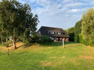 una casa en una colina de hierba con un árbol en Herrliche Ferienwohnung in idyllischer Landschaft, en Morsum