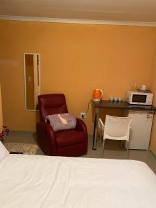 ein Schlafzimmer mit einem Bett, einem Stuhl und einer Mikrowelle in der Unterkunft Mankweng lodge in Polokwane