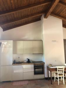 eine Küche mit weißen Schränken, einem Tisch und einem Waschbecken in der Unterkunft La Casa del carrubo di Borgo Carbone in Locri