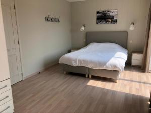 a bedroom with a bed and a wooden floor at Palazzo by Villa Verde -Unique appartment- in De Haan