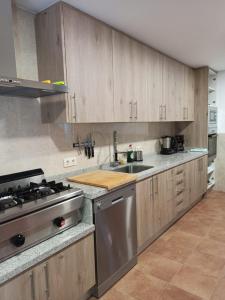a kitchen with wooden cabinets and a stainless steel stove at HOSTEL LA CABAÑUELA in Monleras