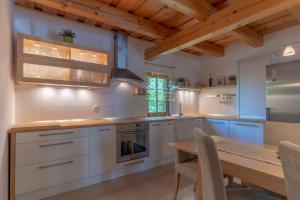 une cuisine avec des placards blancs et une table en bois dans l'établissement Chalet Haloze, à Pristava