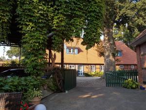 a yellow house with a fence and a tree at Helpens Hof in Salzhausen